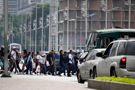 12月2日，在委内瑞拉首都加拉加斯，行人在早高峰时段穿过玻利瓦尔大街。新华社记者李木子摄