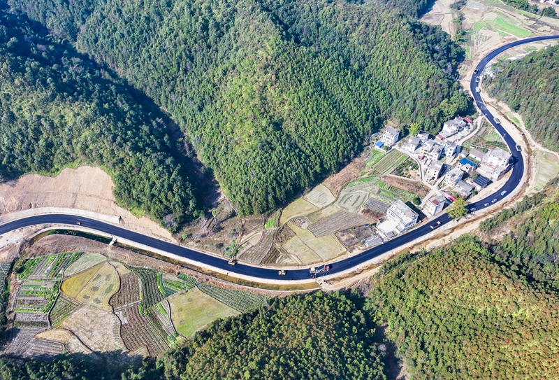 2025年12月30日，江西省赣州市大余县池江镇杨柳村，新铺设的沥青道路蜿蜒于葱郁山林间，串联起民居与村落，为乡村发展打通交通脉络。