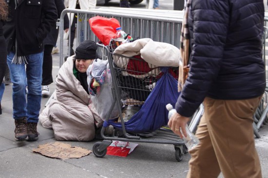 2025年12月31日，在美国纽约街头，无家可归者坐在街边等待帮助。新华社记者张凤国摄