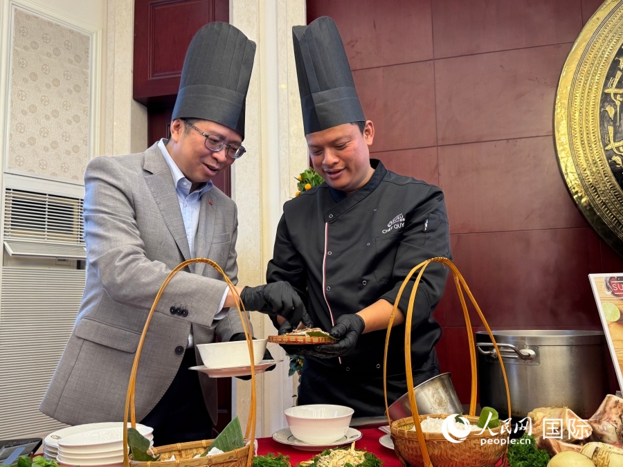 2026年2月5日，越南驻华大使范清平（左）在越南河粉日活动现场体验制作越南河粉。 人民网记者 谢莹摄