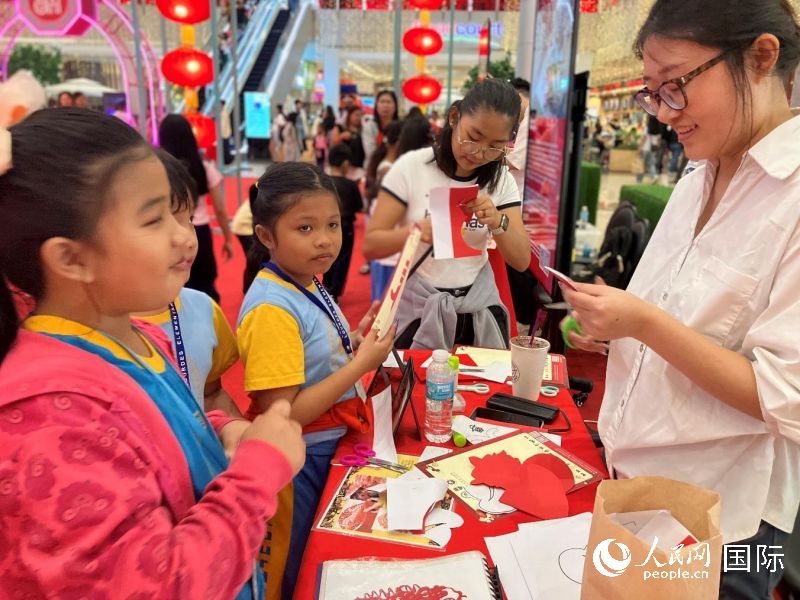 菲律宾儿童在中国文化展台前体验剪纸民俗艺术。人民网记者 樊帆摄