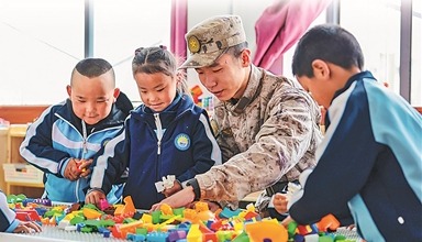 新疆军区某团组织开展“民族团结一家亲”活动。图为在驻地村庄幼儿园，一名战士和小朋友们一起拼积木。袁存皓摄