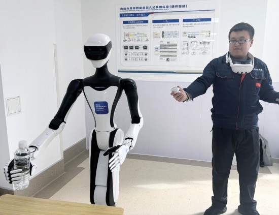 3月18日，一名训练师在青岛康养机器人训练验证中心指导机器人练习抓取物体（手机照片）。新华社发