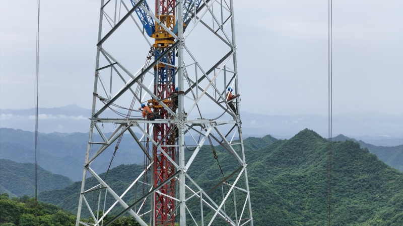 高空作业人员在群山之巅组立铁塔。